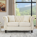 Divanetto Chesterfield in velluto beige, braccioli arrotolati, finiture con borchie