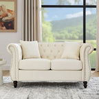 Divanetto Chesterfield in velluto beige, braccioli arrotolati, finiture con borchie