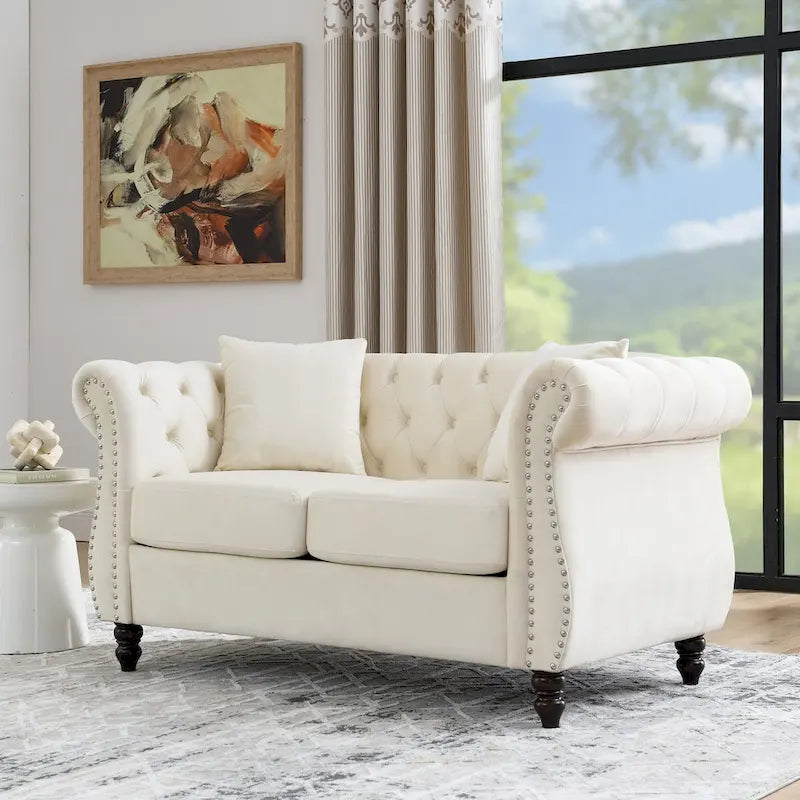 Divanetto Chesterfield in velluto beige, braccioli arrotolati, finiture con borchie