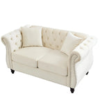 Divanetto Chesterfield in velluto beige, braccioli arrotolati, finiture con borchie