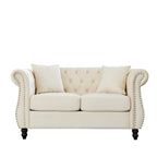Divanetto Chesterfield in velluto beige, braccioli arrotolati, finiture con borchie