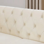 Divanetto Chesterfield in velluto beige, braccioli arrotolati, finiture con borchie